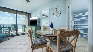 A dining area with a round table, wooden chairs, and a view of the ocean. - 2 Bedroom Gulf  Front Located in Gulf Shores (Gulf Shores)