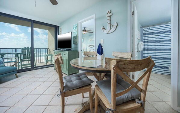 A dining area with a round table, wooden chairs, and a view of the ocean.