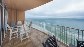 Enjoy the ocean view from this balcony with a table and chairs.