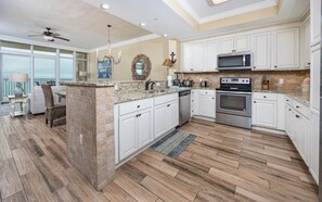 Enjoy cooking in this well-equipped kitchen with a central island, microwave, and oven, offering a view of the ocean through large windows.