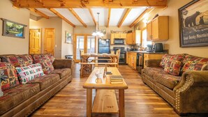 A cozy cabin interior with wooden beams, a dining area, and a kitchen. - *Charming 4BD Lodge w/ Hot Tub! Near Town + GAMES* (Pigeon Forge)