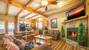 A cozy living room with a fireplace, wooden beams, and a stone fireplace surround. - *Charming 4BD Lodge w/ Hot Tub! Near Town + GAMES* (Pigeon Forge)