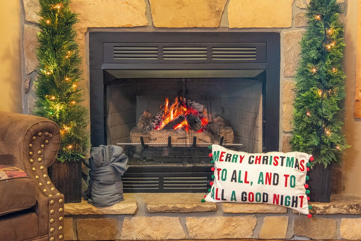 A fireplace with a Christmas tree and a sign that reads "MERRY CHRISTMAS TO ALL, AND TO ALL A GOOD NIGHT".