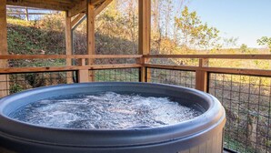 Un jacuzzi en una cabaña de madera con vistas a árboles y colinas.