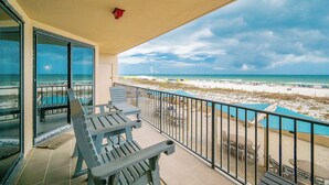 Un balcon avec vue sur la plage et l’océan, comprenant un espace salon extérieur et une piscine.
