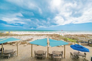 A beachside patio with outdoor seating and a view of the beach and ocean. - Popular Phoenix X  3bedroom condo 213 (Orange Beach)