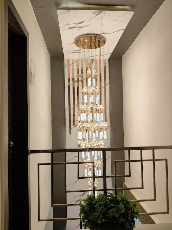 A modern interior with a marble ceiling, a decorative light fixture, and a geometric railing.