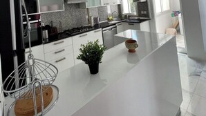 Een moderne keuken met witte kasten, een centraal eiland en een roestvrijstalen afzuigkap.