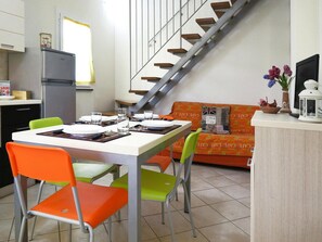 A compact living space with a dining area, a kitchenette, and a staircase.