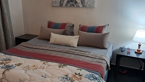 A neatly made bed with floral bedding, a bedside table with a lamp, and a painting on the wall. - Lovely loft in the heart of Casablanca  (Casablanca)