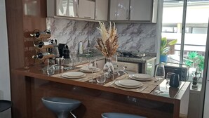 A modern kitchen with marble countertops, a built-in stove, and a dining area set with plates and glasses. - Lovely loft in the heart of Casablanca  (Casablanca)