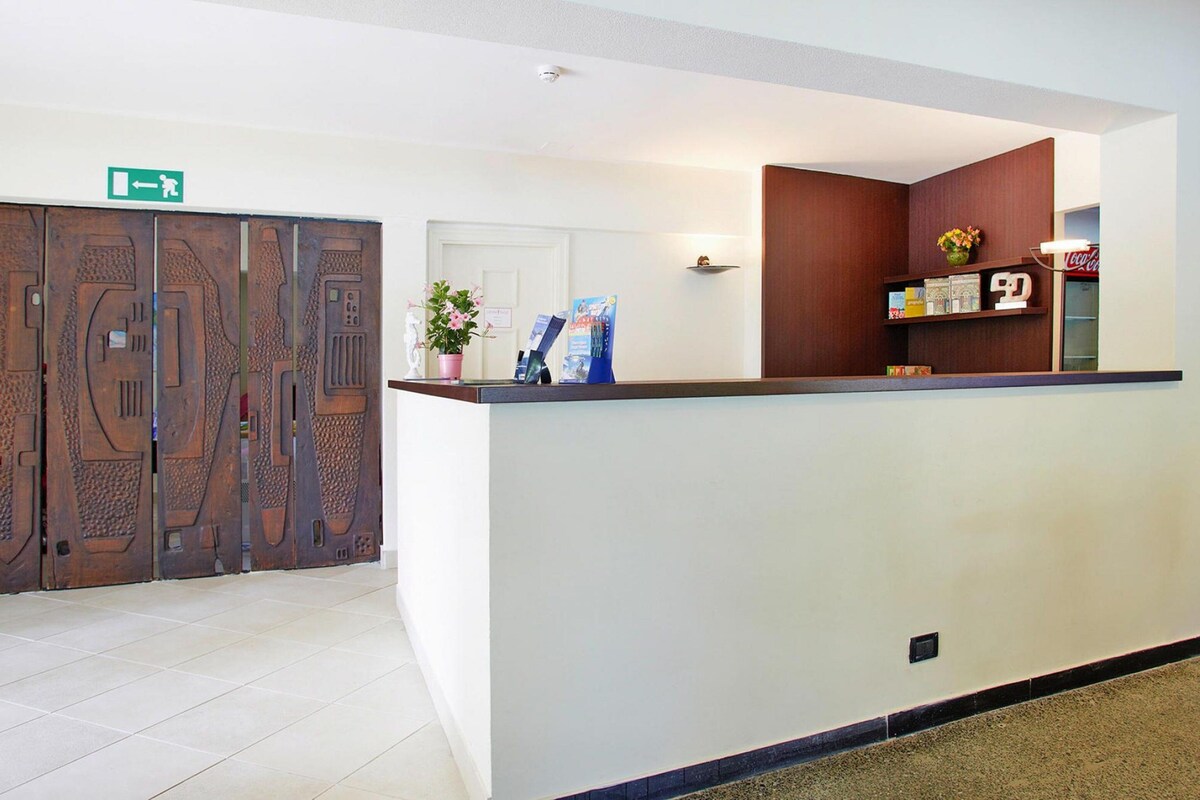 A reception area with a modern counter, a door with a unique design, and a small shelf with items.