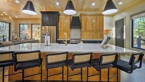 A modern kitchen with a large island, wooden cabinets, and pendant lighting. - Heated Pool+Hot Tub+Fire Pit+Fishing Pond=Relaxing Getaway! (Broken Bow)