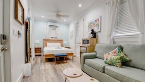A modern hotel room with a bed, a sofa, a small table, and a TV. - Harbor Walk Hideaways | Group Compound In Old Town, Pool! (Key West)