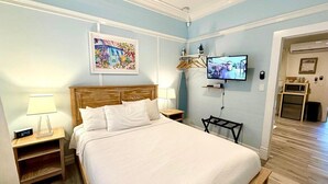A neatly arranged bedroom with a bed, bedside tables, a TV, and a painting on the wall. - Atocha Cottage at Harbor Walk Hideaways | 2 Blocks From Duval! (Key West)