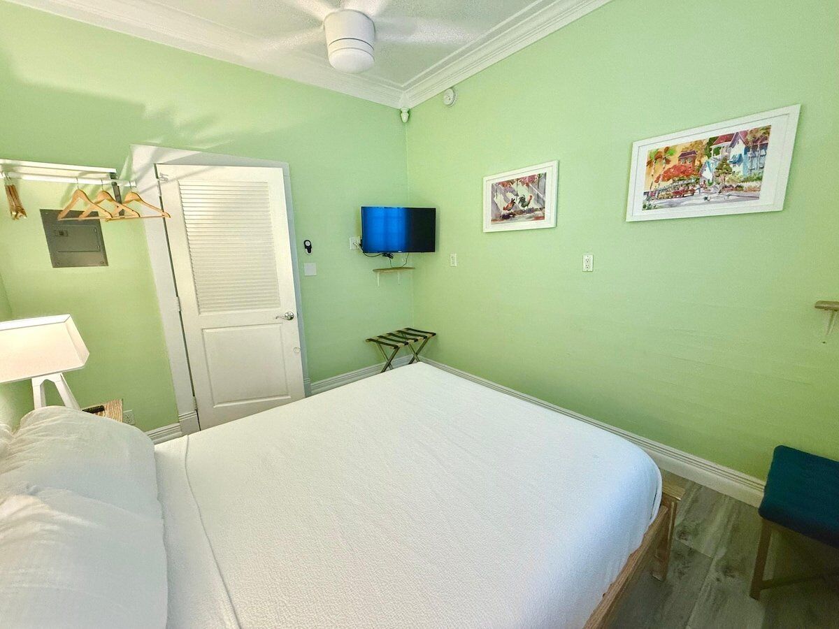 Een kamer met een bed, een aan de muur bevestigde televisie en twee ingelijste foto's.
