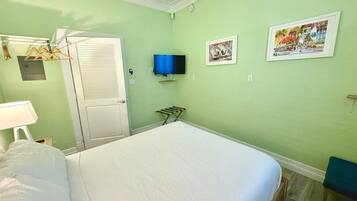 Een kamer met een bed, een aan de muur bevestigde televisie en twee ingelijste foto's.