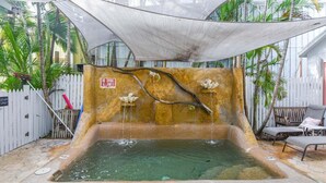 A small outdoor pool with a waterfall feature, surrounded by a white fence and palm trees. - Atocha Cottage at Harbor Walk Hideaways | 2 Blocks From Duval! (Key West)