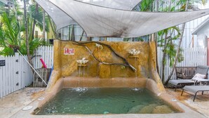 A pool area with a stone wall, a no diving sign, and lounge chairs. - Pilar Cottage | Spectacular Studio w/ Shared Pool (Key West)