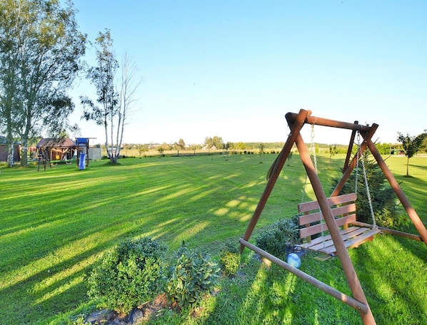 A grassy outdoor area with a wooden swing set and a small play structure in the background. - Comfortable Bungalows With a Fireplace and Terrace, Jaroslawiec (Postomino)