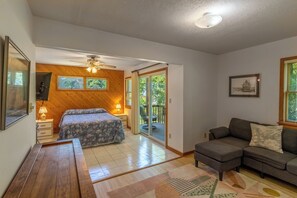 A bedroom with a bed, a nightstand, a ceiling fan, and a sliding glass door leading to a balcony. - Classic Outer Banks soundside beach house near Duck Town Park! (Duck)
