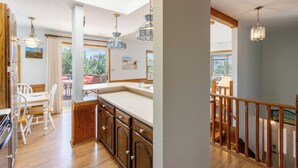 A kitchen with wooden cabinets, a white countertop, and hanging pendant lights.