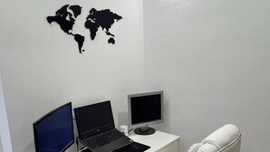 Een moderne kantoorruimte met een wit bureau, twee monitoren, een laptop en een witte bureaustoel.