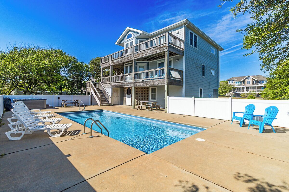 A two-story building with a swimming pool, outdoor seating, and a staircase leading to the upper level.