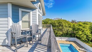 Ein Haus mit Pool, zwei Adirondack-Stühlen und einer Holzterrasse.