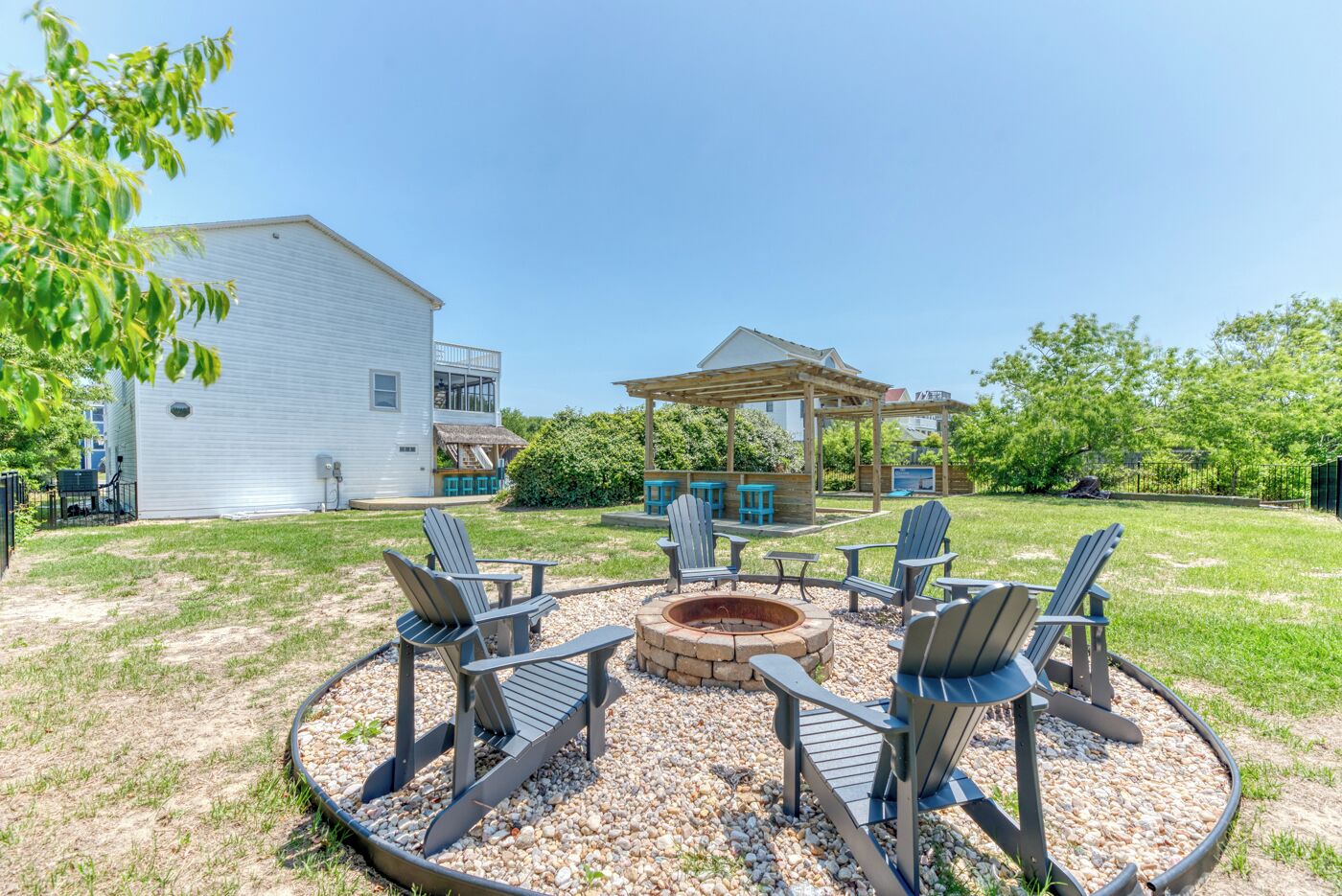 Un jardin avec un foyer, un espace salon extérieur et une pergola.