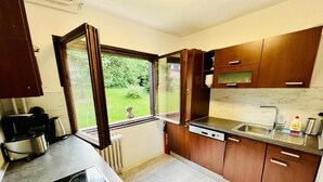 Una cocina compacta con estufa a gas, horno empotrado, pileta y muebles de madera.