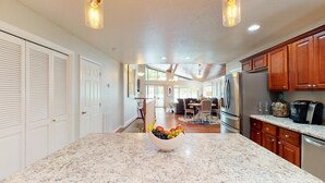 A kitchen with a granite countertop, a stainless steel refrigerator, and wooden cabinets.