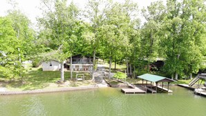 A lakeside property with a dock, a covered pavilion, and a house with a deck.