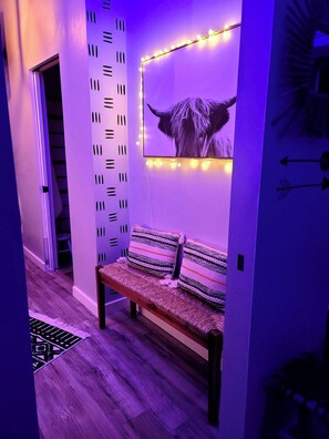 Un couloir avec un banc, un mur muni d’un luminaire et une porte.