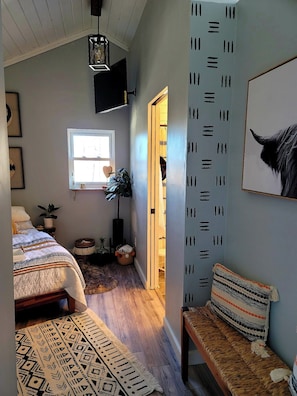 A cozy bedroom with a bed, bedside table, lamp, and a window. - Boho Mtn Vibe'z~ Hot Tub+Fire Pit~ 3 mins to BRP! (Spruce Pine)