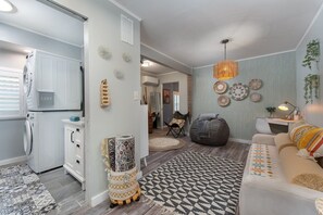 A modern living space with a kitchen, seating area, and decorative wall art. - Boho Mtn Vibe'z~ Hot Tub+Fire Pit~ 3 mins to BRP! (Spruce Pine)