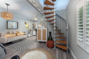 A modern interior with a spiral staircase, a sofa, a cabinet, and a patterned rug. - Boho Mtn Vibe'z~ Hot Tub+Fire Pit~ 3 mins to BRP! (Spruce Pine)