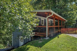 Un petit bâtiment d’un seul étage, doté d’un porche et entouré d’arbres et d’une clôture en bois.
