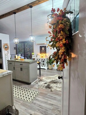 A modern kitchen with a central island, pendant lights, and a decorative floral arrangement.