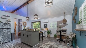 A modern kitchen with a central island, pendant lights, and a rustic rug. - “Little Blue Cabin • Cozy Boho Hideaway • Jacuzzi, Fire Pit & Close to BRP” (Spruce Pine)