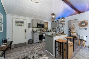 A modern kitchen with a central island, bar stools, and pendant lighting.