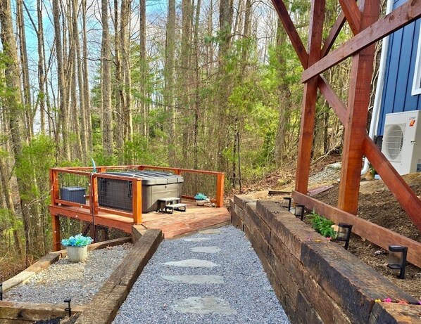 A deck with a grill and seating area, surrounded by a wooden deck and a forested area.