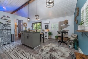 A modern kitchen with a central island, pendant lighting, and a rustic rug.