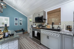 A modern kitchen with a built-in microwave, stainless steel appliances, and a patterned backsplash. - Boho Mtn Vibe'z~ Hot Tub+Fire Pit~ 3 mins to BRP! (Spruce Pine)
