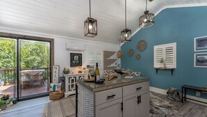 A modern kitchen with a large island, pendant lighting, and a view of the outdoor patio. - “Little Blue Cabin • Cozy Boho Hideaway • Jacuzzi, Fire Pit & Close to BRP” (Spruce Pine)