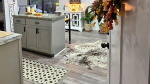 A modern kitchen with a central island, pendant lights, and a decorative floral arrangement. - “Little Blue Cabin • Cozy Boho Hideaway • Jacuzzi, Fire Pit & Close to BRP” (Spruce Pine)