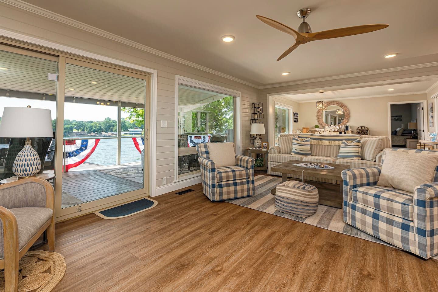 A spacious living room with a large window overlooking a deck, a ceiling fan, and a fireplace.