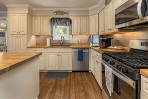 A kitchen with a central island, stainless steel appliances, and light-colored cabinetry.