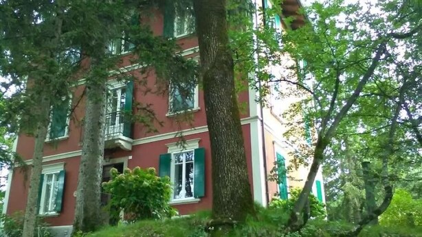Een rood gebouw met groene luiken en een balkon.