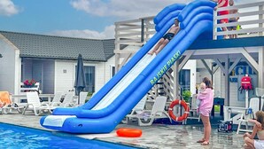A pool area with a blue inflatable slide, lounge chairs, and a lifebuoy. - Holiday Home Near Bukowo Lake and Beaches (Darlowo)